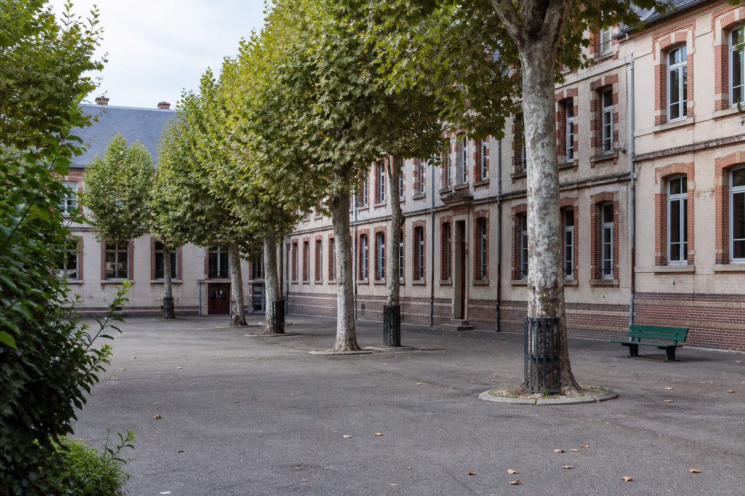 Cour d’un lycée français, bâtiments de brique et arbres.