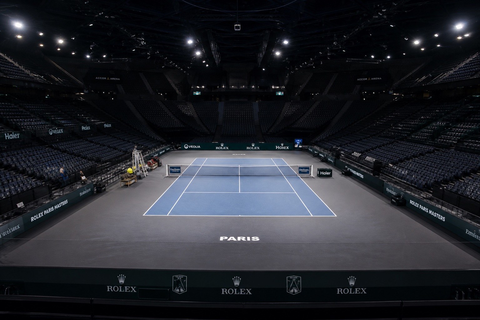 Court de tennis indoor, gradins et éclairage de salle.